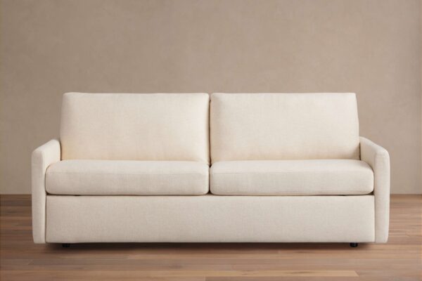Kipton Luxury Sleeper Sofa in beige fabric, shown from the front with plush seat and back cushions, set on a wooden floor.