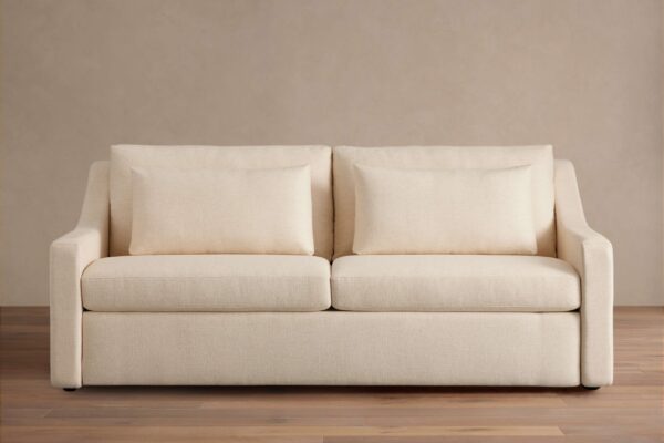 Front view of the Ashby Luxury Sleeper Sofa, a modern two-seater in cream-colored fabric with two rectangular throw pillows.