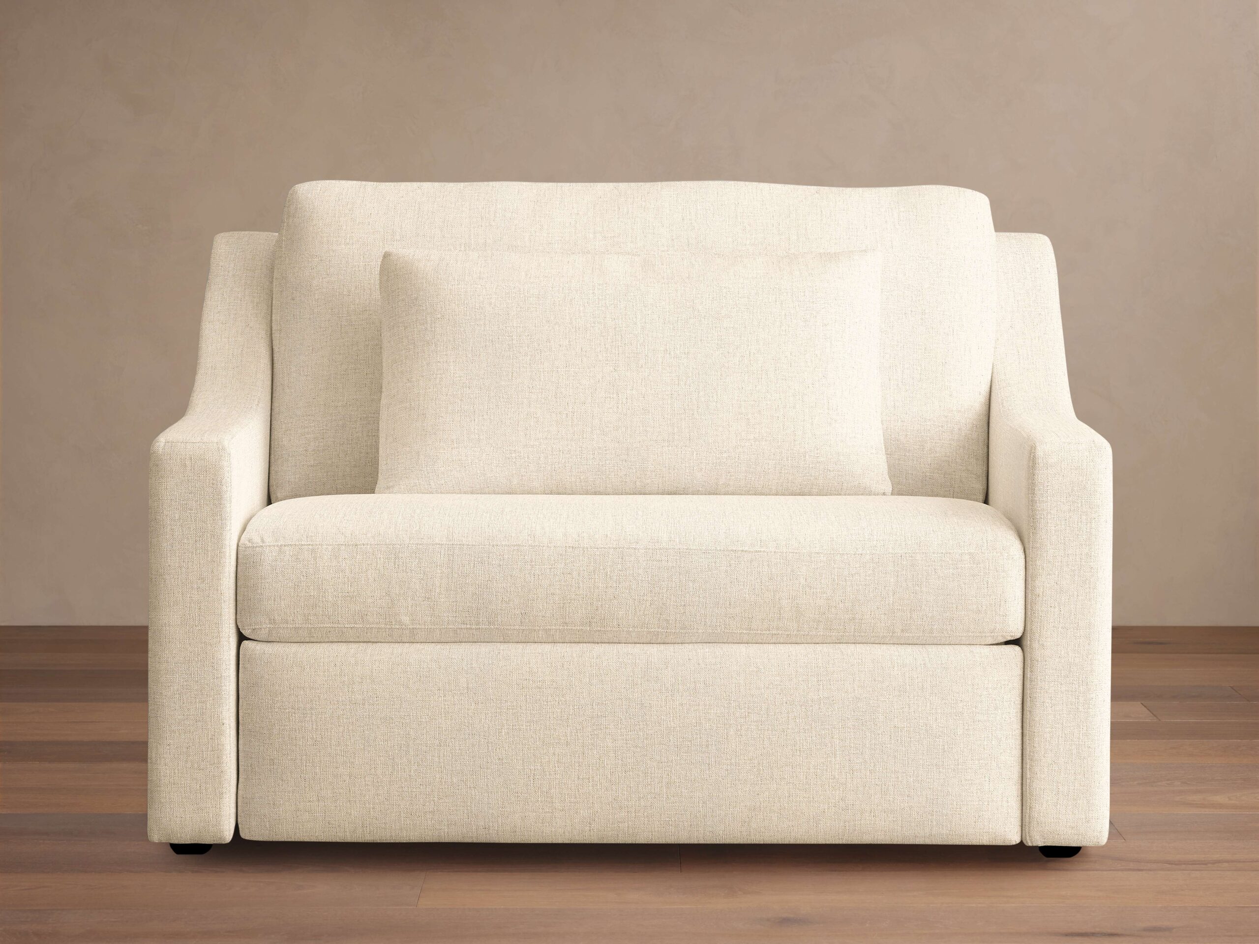 Front view of Ashby Luxury Twin Sleeper Chair in beige fabric, featuring plush seat and back cushions, with wooden floor and neutral wall background.
